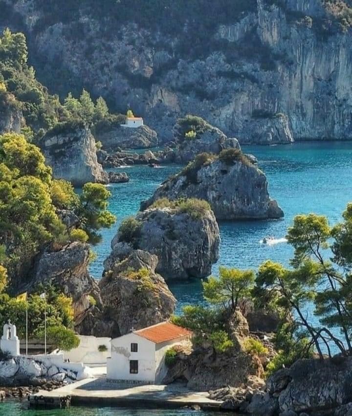 Island of the Virgin Mary with chapel surrounded by the Ionian Sea and pine-fringed coastline in Parga, Greece.