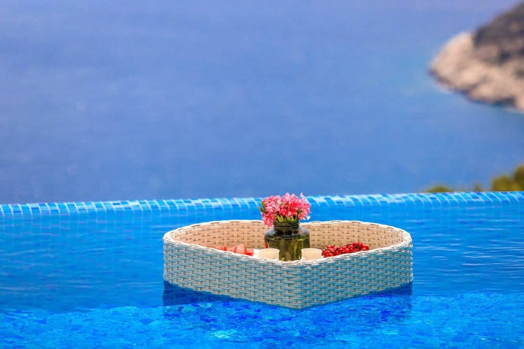 Infinity-edge swimming pool at a romantic Kalkan villa, overlooking the sea with a heart-shaped tray of treats — the perfect setting for honeymoons in Kalkan.