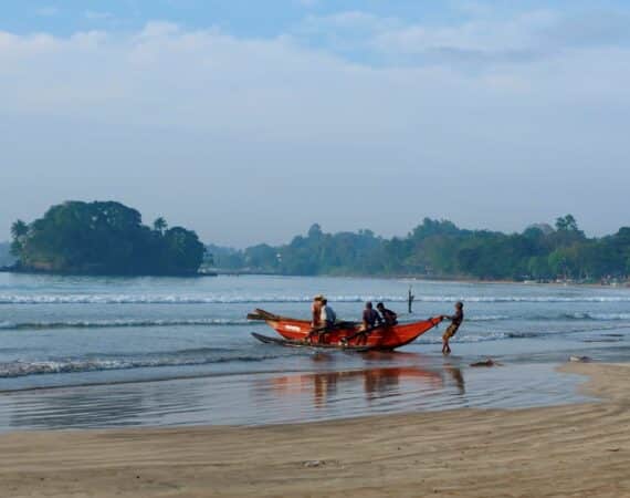 Fishermen bringing in colourful boats on Weligama Beach near Tekanda Lodge, with golden sand, gentle surf, and early morning light on the south coast of Sri Lanka.