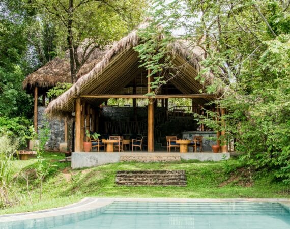 Gal Oya Lodge main lodge by day, featuring open-air sitting area with natural wood furnishings and views over the surrounding forest in Gal Oya National Park, Sri Lanka.