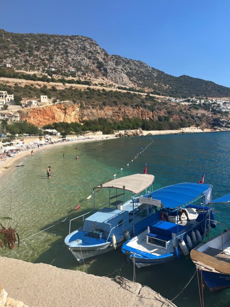 Sweeping view of Kalkan’s bay in August, with whitewashed villas, terracotta rooftops, and the turquoise Mediterranean stretching out beneath clear summer skies.