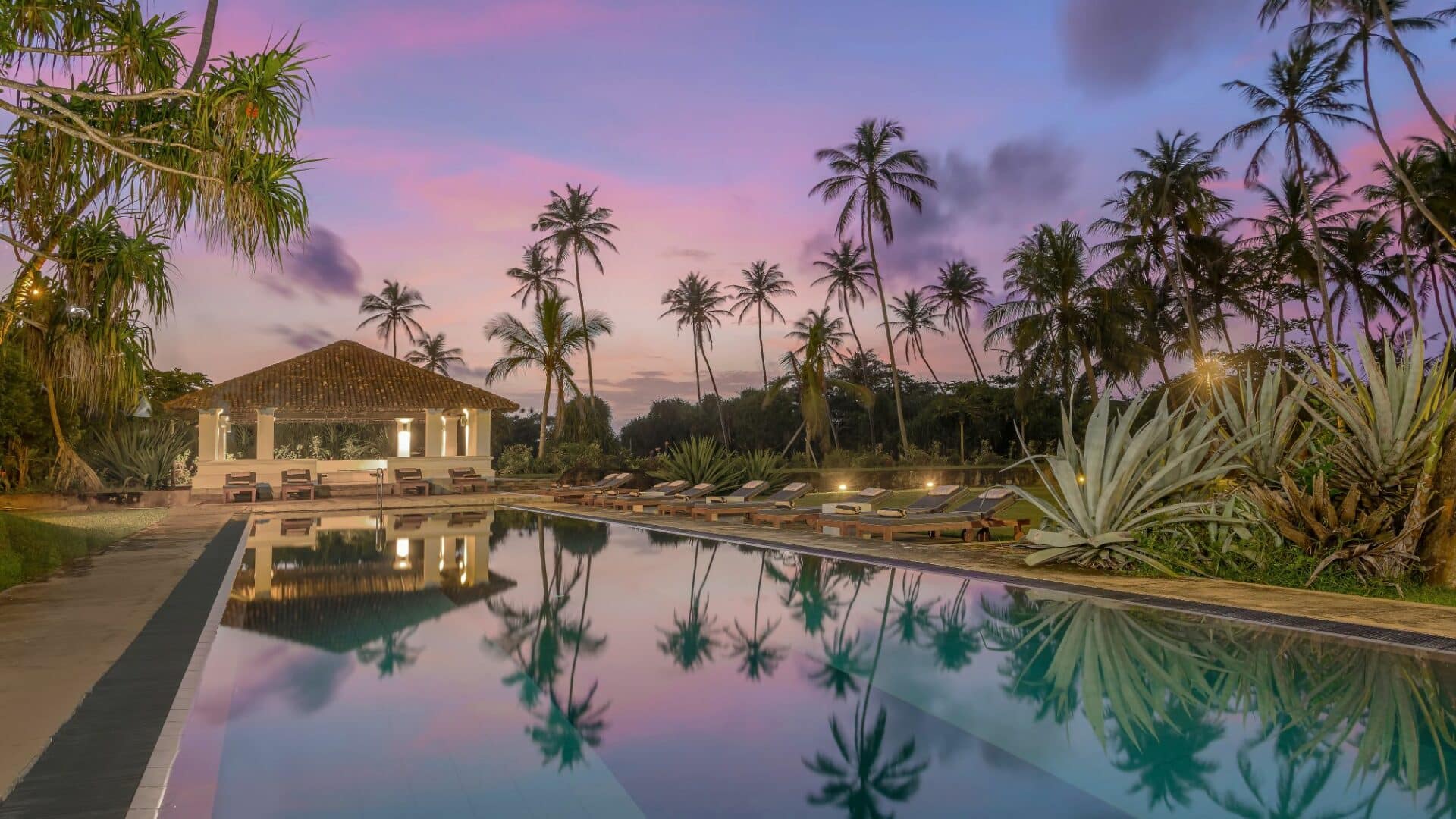 The Villa Bentota and swimming pool at sunset under a rainbow of pink skies