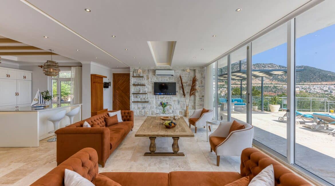 Villa Oasis Kalkan open plan sitting area and kitchen with floor to ceiling glass windows framing the poolscapes and surrounding views