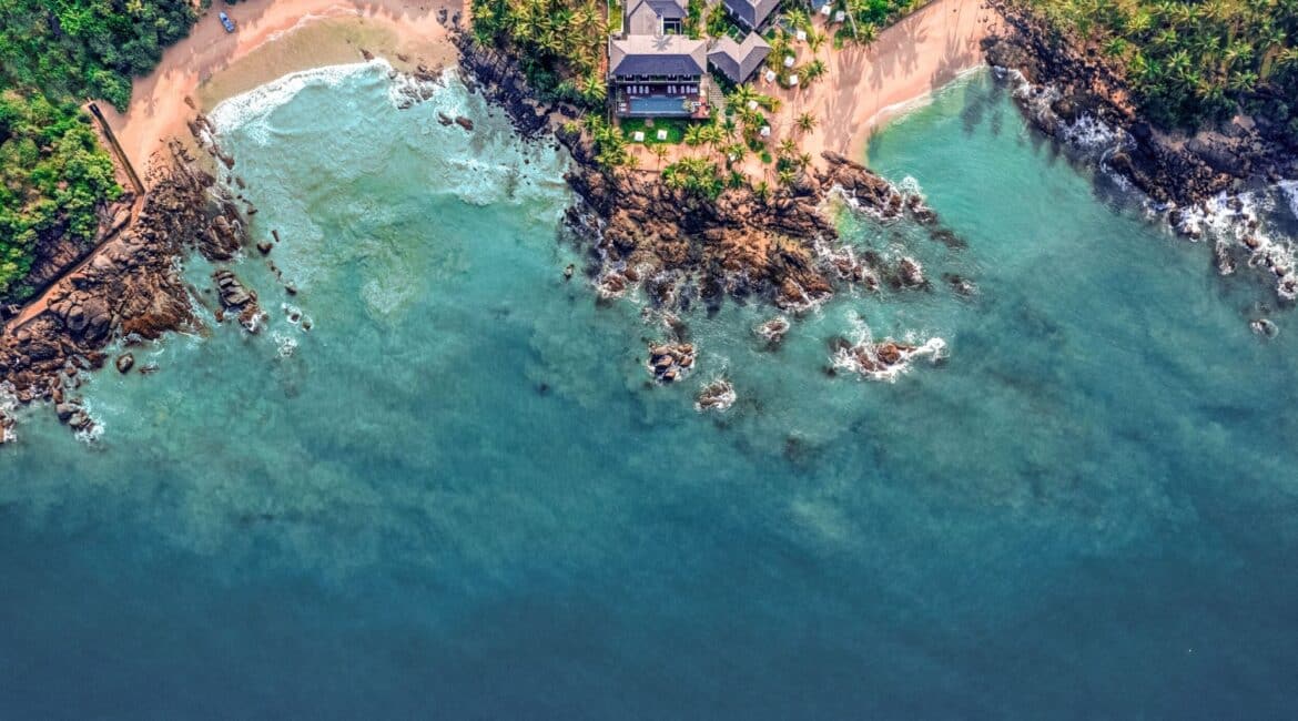Aerial view of Ahu Bay Sri Lanka showing the hotel, sandy beach, and the vast Indian Ocean stretching to the horizon.