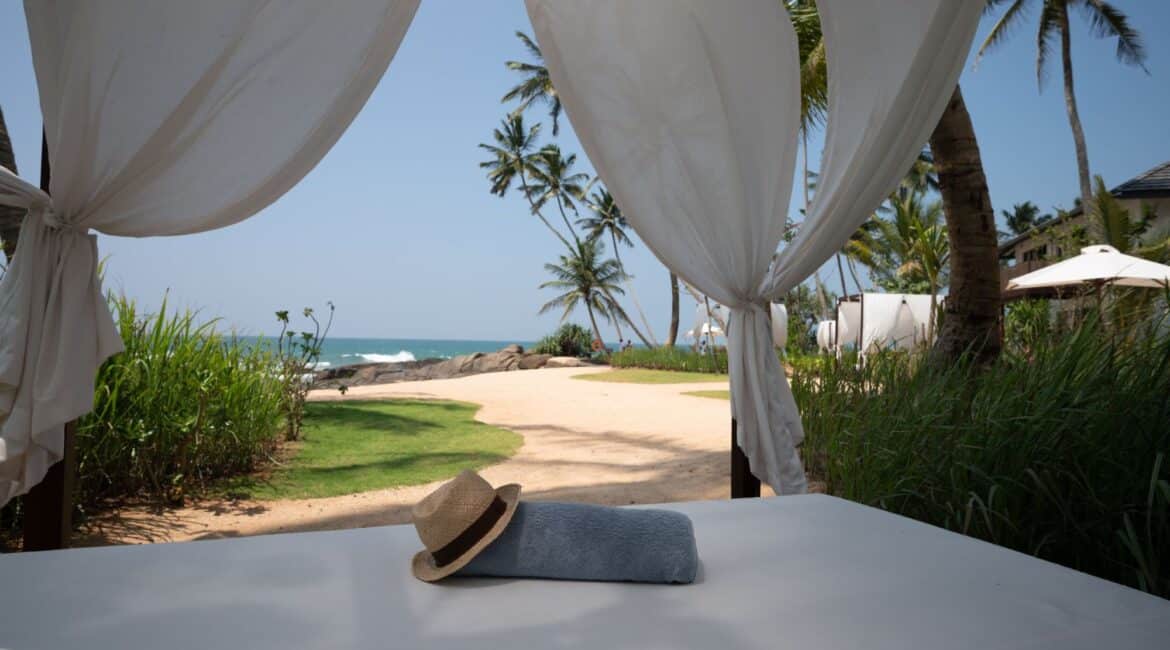Beachside cabanas at Ahu Bay Sri Lanka with shaded seating overlooking the sand and ocean.