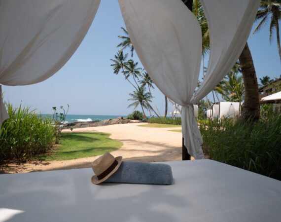 Beachside cabanas at Ahu Bay Sri Lanka with shaded seating overlooking the sand and ocean.