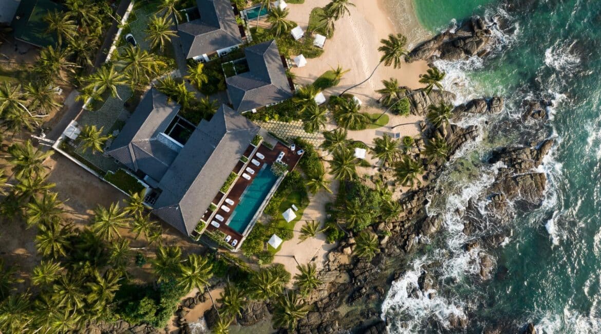 Drone view of Ahu Bay Sri Lanka perched on a rocky outcrop with the Indian Ocean in front and lush jungle in the background.