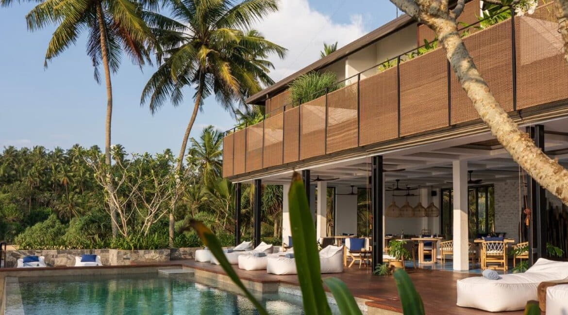 Glorious view of Ahu Bay Sri Lanka showing the hotel building, infinity swimming pool, and lush tropical gardens overlooking the ocean.