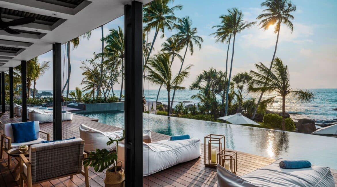 Stunning sunset views over the infinity pool at Ahu Bay Sri Lanka with the ocean and palm trees in the background.