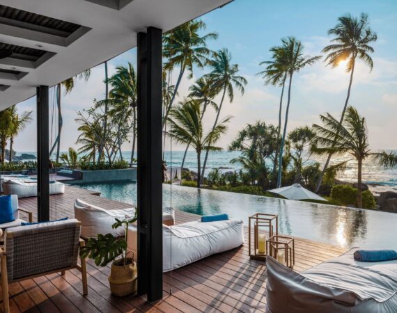 Stunning sunset views over the infinity pool at Ahu Bay Sri Lanka with the ocean and palm trees in the background.
