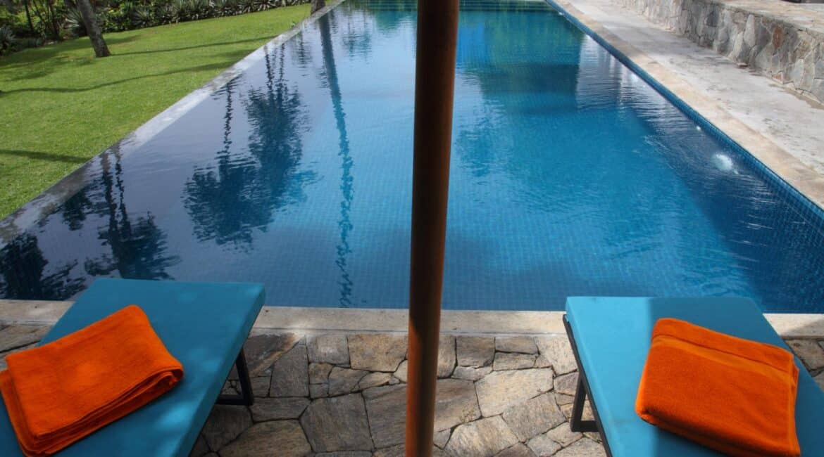 Coco Tangalla Hotel near Tangalle, Sri Lanka – inviting day beds arranged around the ocean-facing swimming pool, framed by palm trees and coastal views.