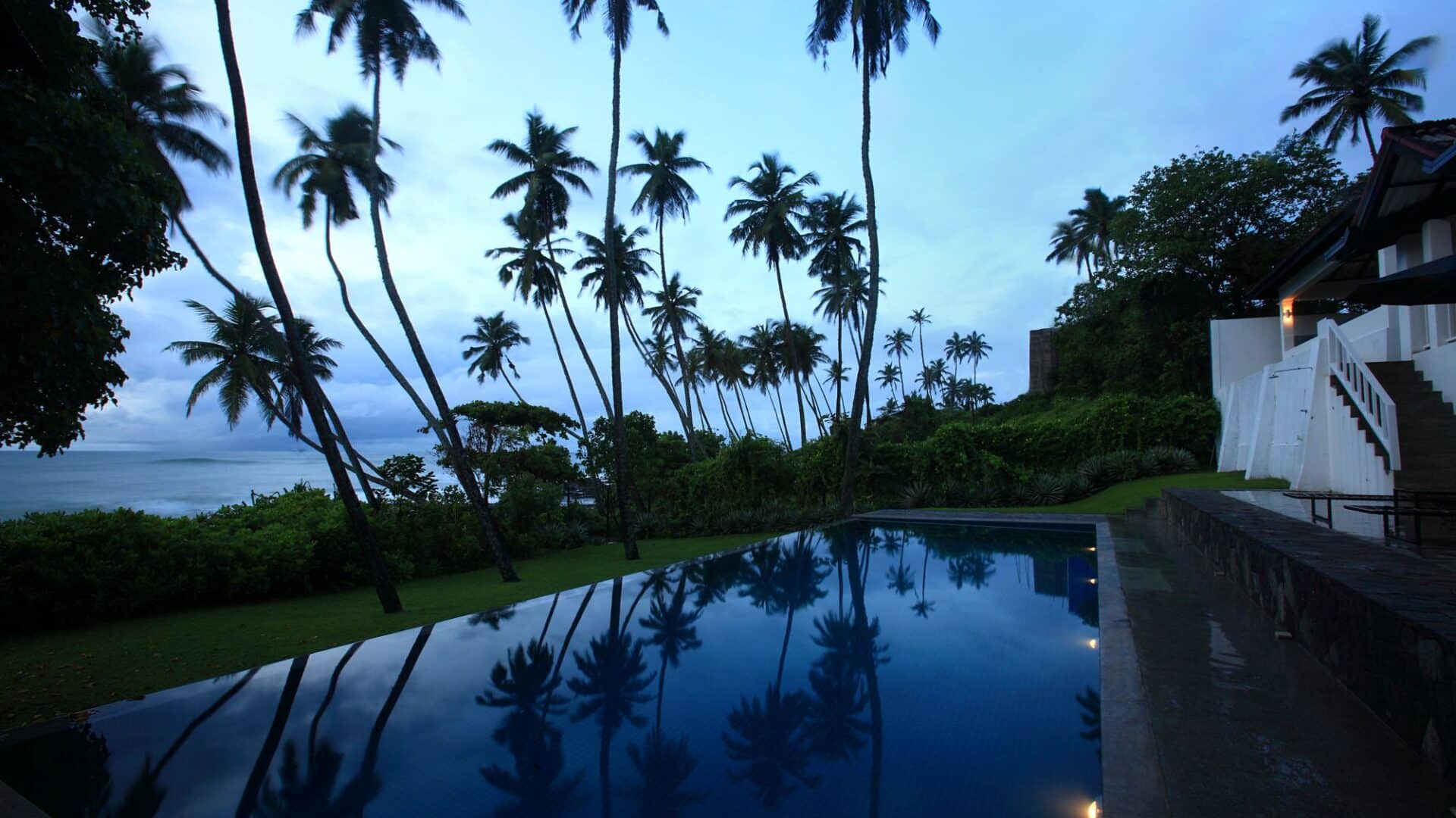 Coco Tangalla Hotel near Tangalle, Sri Lanka — tranquil poolside scene at dusk with silhouetted palm trees against the evening sky.