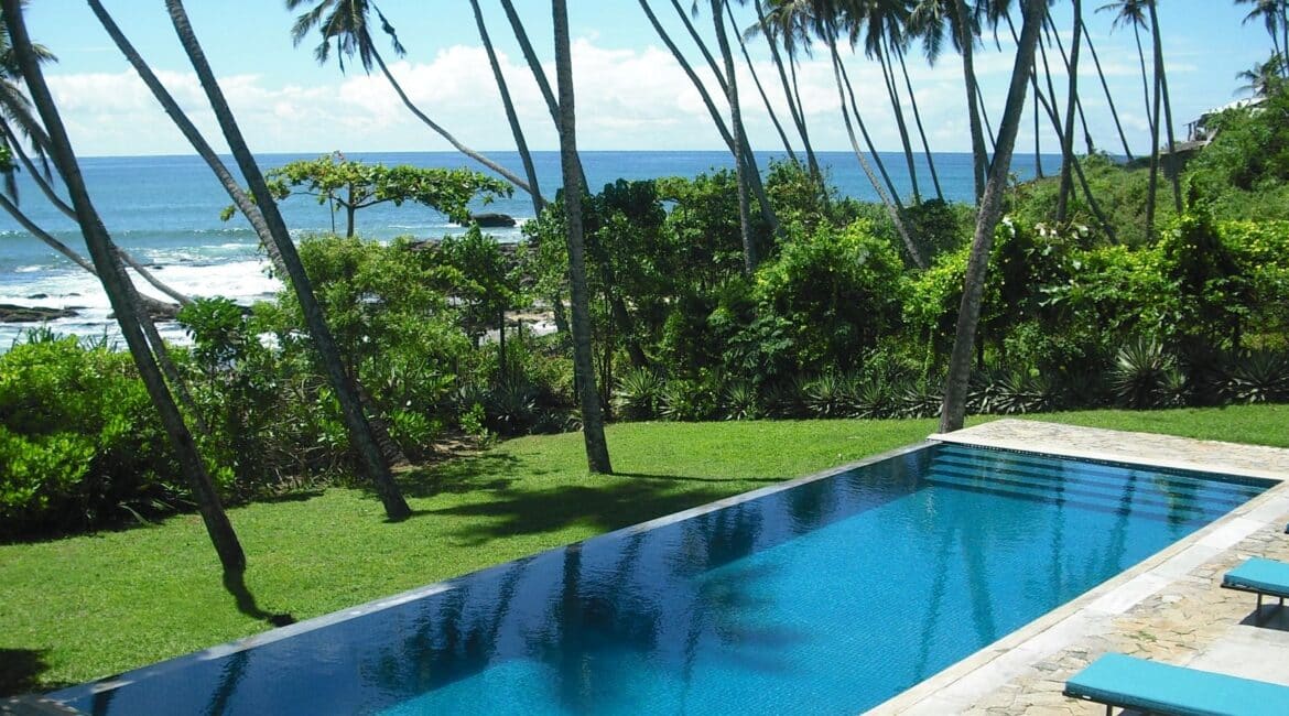 Infinity swimming pool at Coco Tangalla near Tangalle, Sri Lanka, surrounded by lawns, palm trees, and overlooking the Indian Ocean