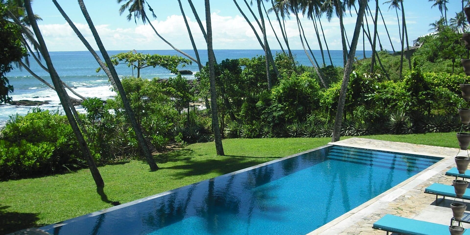Infinity swimming pool at Coco Tangalla near Tangalle, Sri Lanka, surrounded by lawns, palm trees, and overlooking the Indian Ocean