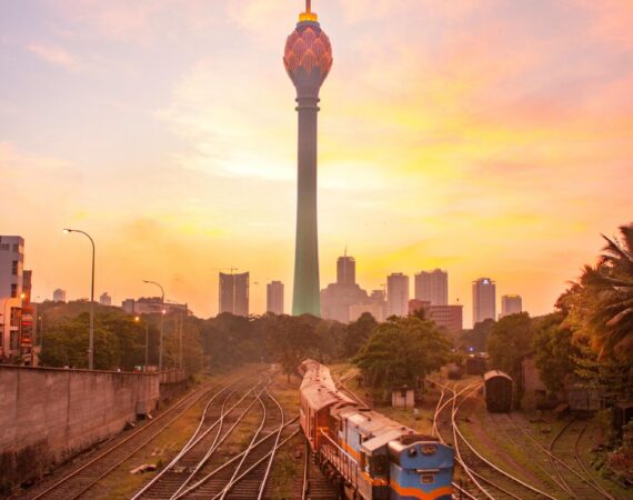 otus Tower rising above the Colombo skyline, with trains passing in the foreground – a striking blend of modern Sri Lanka and everyday city life.