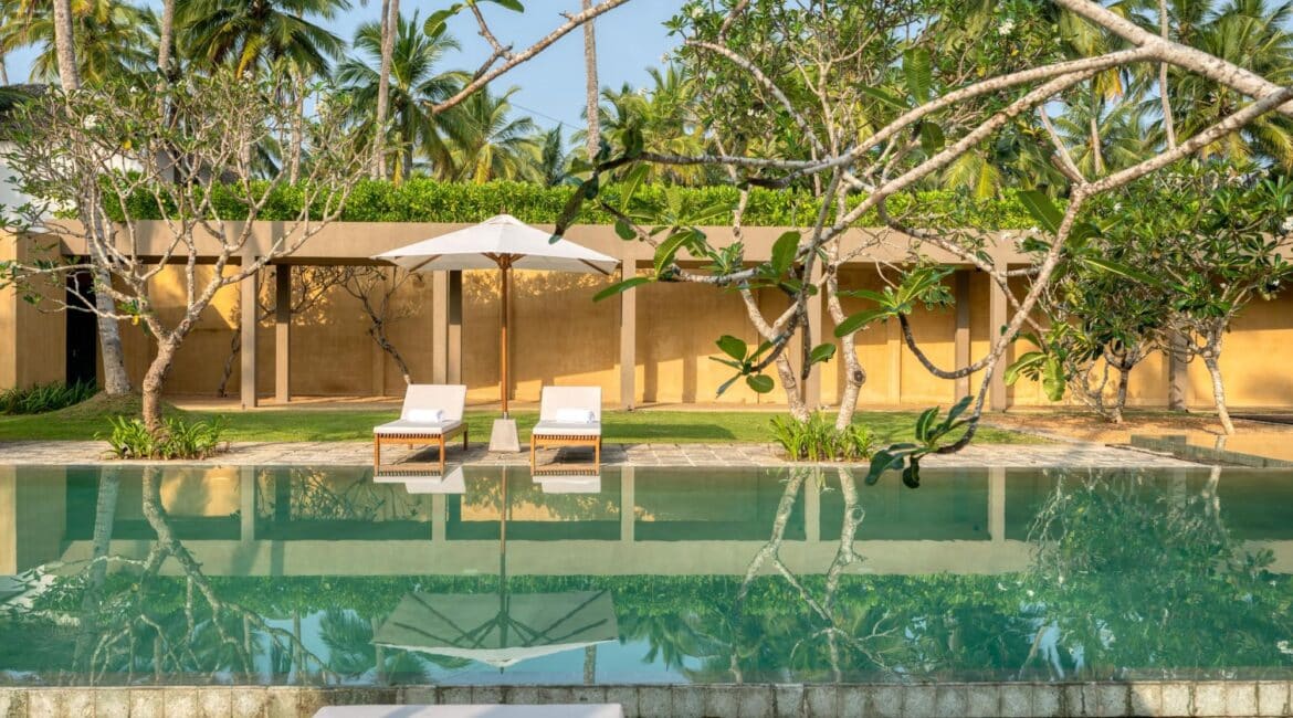 Kayaam House Sri Lanka – serene swimming pool bordered by manicured lawns, tropical gardens, and swaying palms.