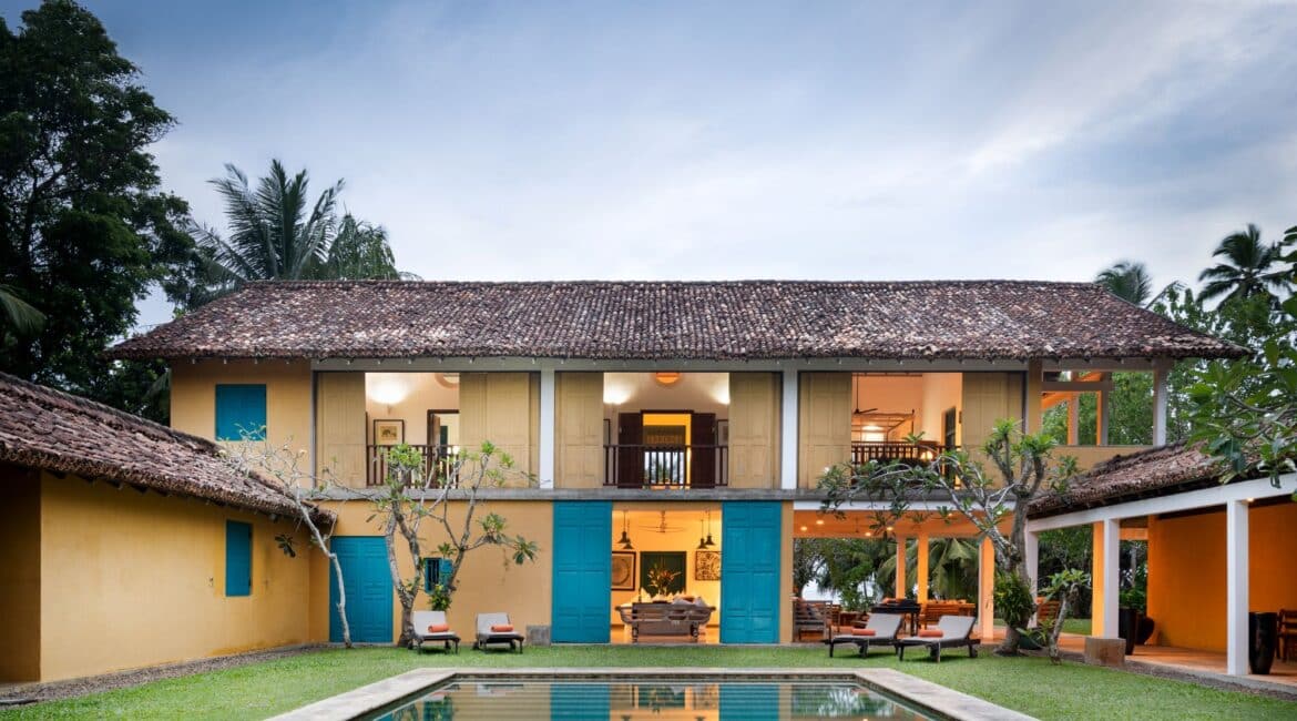 The Last House Tangalle, Sri Lanka – vibrant yellow exterior with colonial charm, set beside a turquoise swimming pool and tropical gardens.