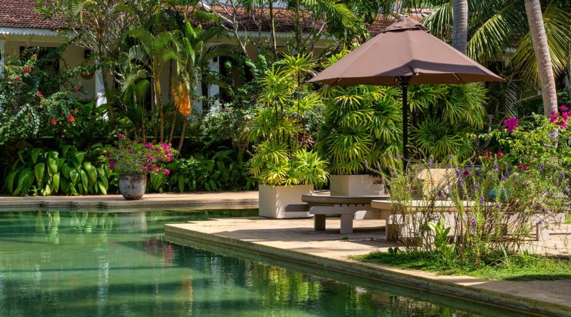 Swimming pool surrounded by tropical pathways and lush lawns at Why House Sri Lanka retreat