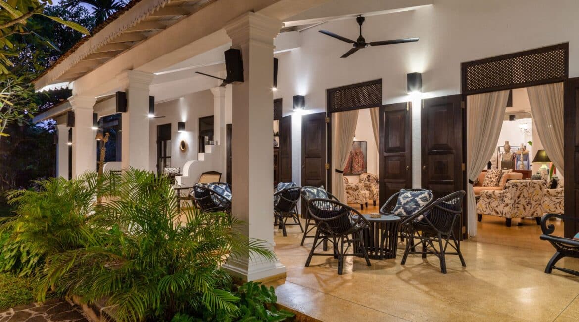 Shaded veranda surrounded by frangipani and palm trees at Why House Sri Lanka