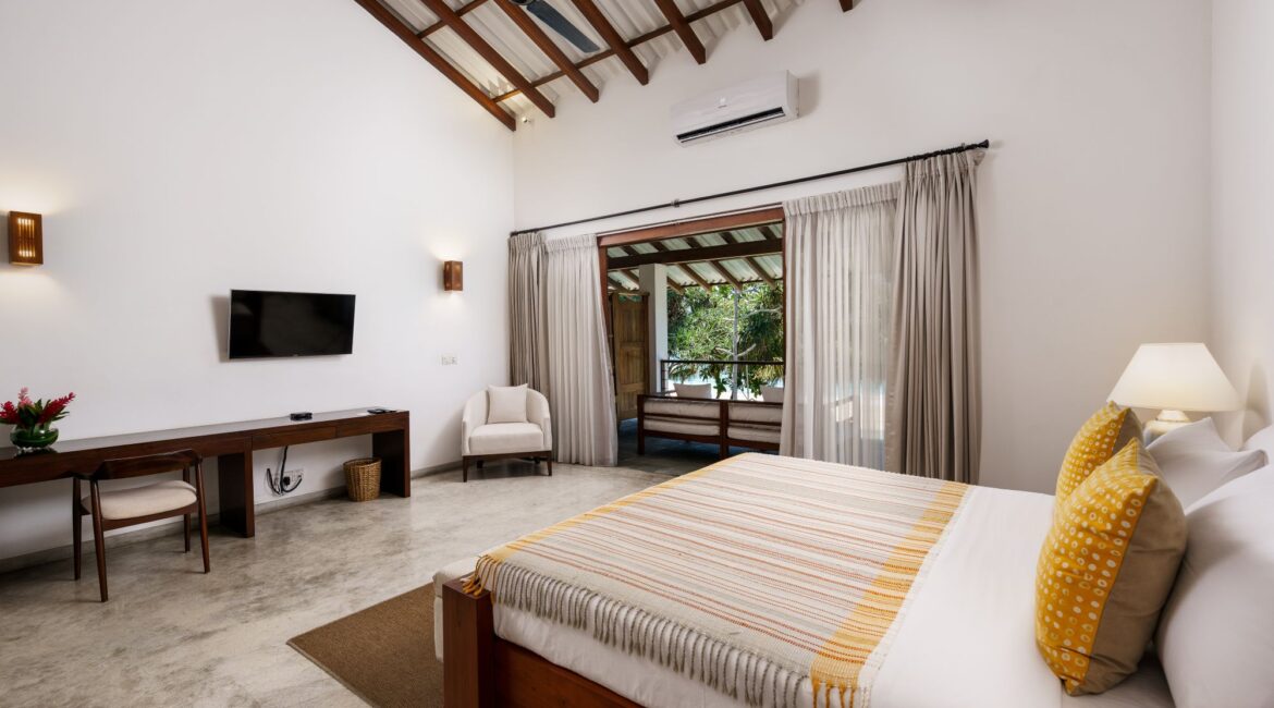 Deluxe Ocean Room at Lantern Boutique Hotel Sri Lanka – stylish bedroom with wooden fixtures, a neutral décor palette, and vibrant yellow accents adding warmth and character