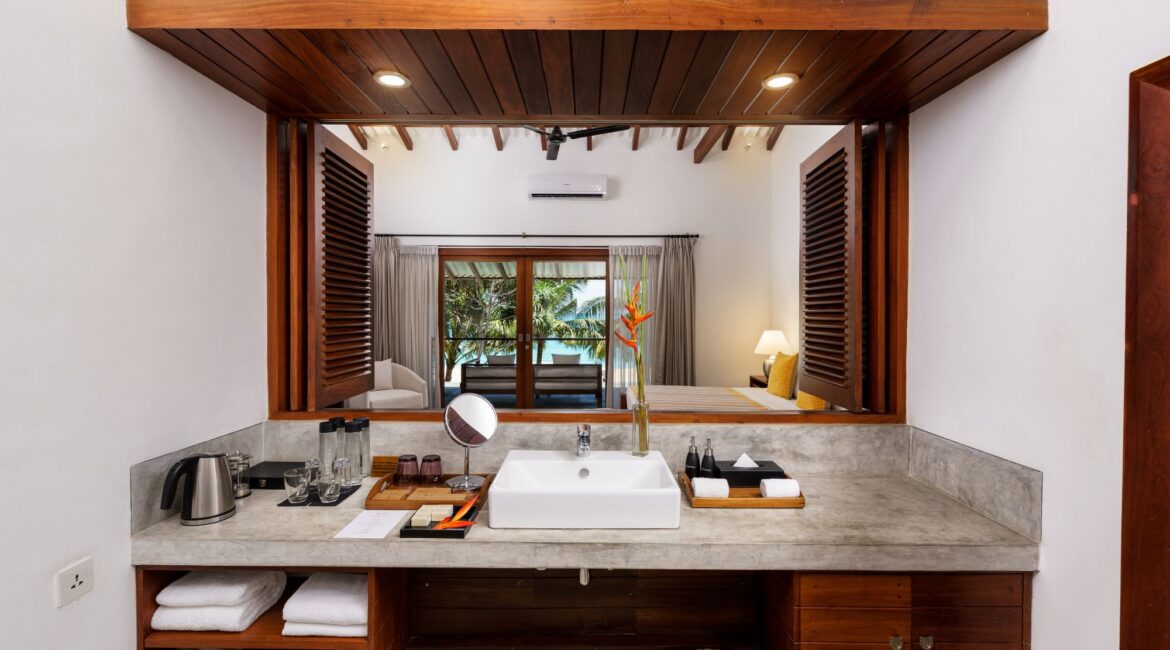 Deluxe Ocean Room at Lantern Boutique Hotel Sri Lanka – en suite bathroom with open shutters looking through to the bedroom, furnished balcony, and sweeping sea views
