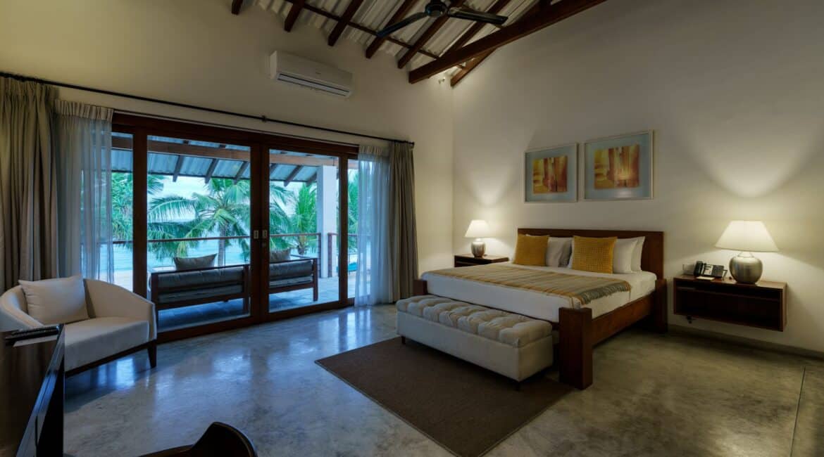 Deluxe Ocean Room at Lantern Boutique Hotel Sri Lanka – spacious bedroom with bed, armchairs and French windows opening onto a furnished terrace with breathtaking beach and ocean views