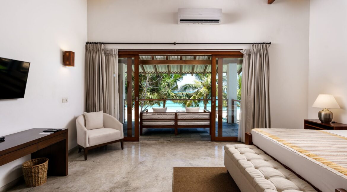 Deluxe Ocean Room at Lantern Boutique Hotel Sri Lanka – furnished balcony with a cosy sofa overlooking the beach and swaying palm trees in the tropical breeze