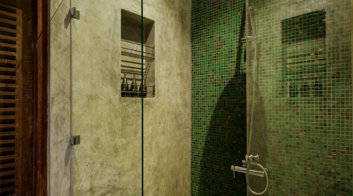 Deluxe Ocean Room at Lantern Boutique Hotel Sri Lanka – en suite bathroom with waterfall shower, WC, and elegant green tiling