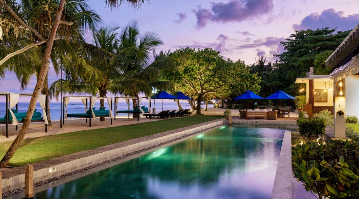 Lantern Boutique Hotel Sri Lanka – dusk view of the beach, glowing hotel exteriors, illuminated swimming pool, and manicured gardens with the Indian Ocean in the background