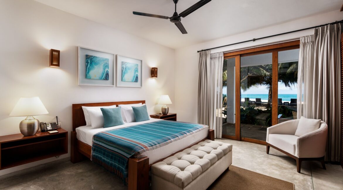 Ocean Suite at Lantern Boutique Hotel Sri Lanka bright bedroom with floor-to-ceiling glass windows opening onto a furnished terrace with sea views