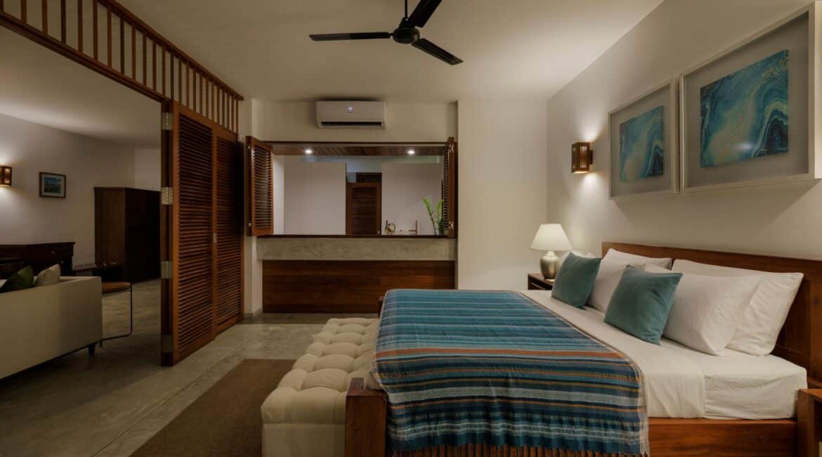 Ocean Suite at Lantern Boutique Hotel Sri Lanka – elegant open-plan design with high ceilings, neutral décor accented by blue tones, and a partition separating the bedroom from the sitting area