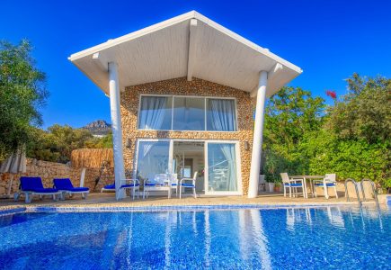 Exterior of Likya Pavilion Pool House in Kalkan with large private pool, stone façade, and floor-to-ceiling glass walls overlooking spacious villa-style suite