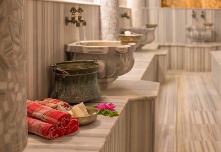 A marble hammam steam room in Kalkan with copper bowls and towels laid out for a Turkish bath ritual