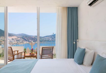 Oasis Hotel Plunge Pool Suite – elegant bedroom opening onto a private furnished balcony with panoramic sea views, a romantic Kalkan hideaway.